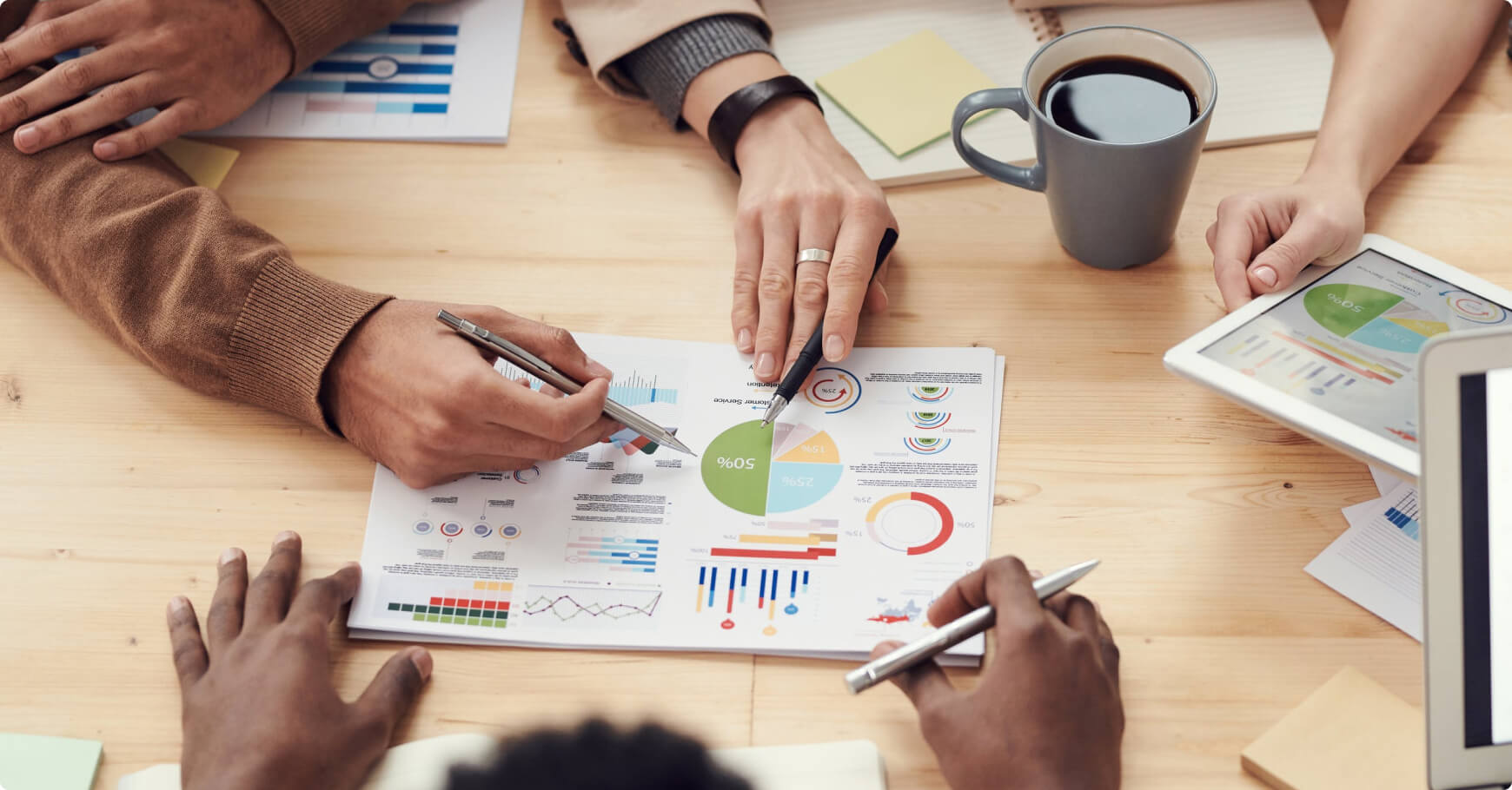 Professionals utilizing a laptop and tablet, examining graphs and papers that highlight trends in e-commerce personalization.